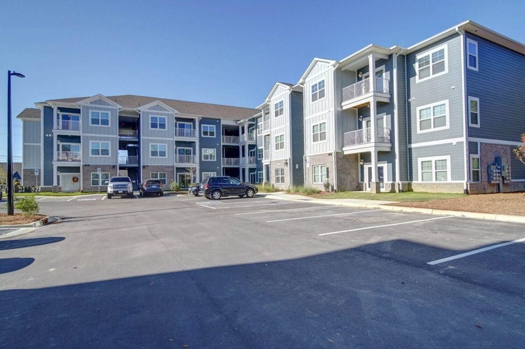 Arka Heights in Monroe, three-storey apartment buildings in grey and blue siding beside the car park.