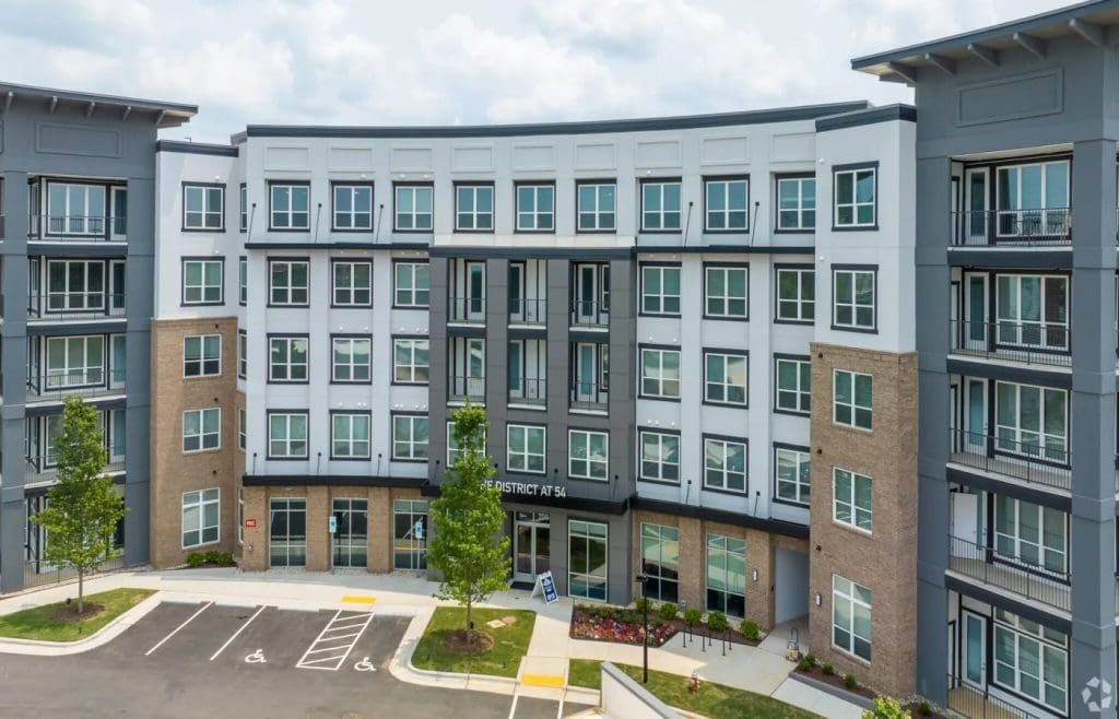 The District 54 apartment building in Raleigh, a five-storey block in grey and cream with ground-floor retail units.