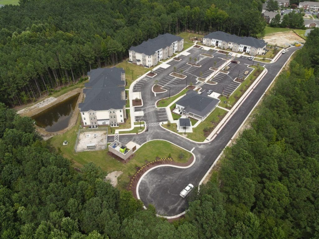 Aerial view of East Haven Apartments in Rocky Mount, apartment buildings and parking beside woodland.