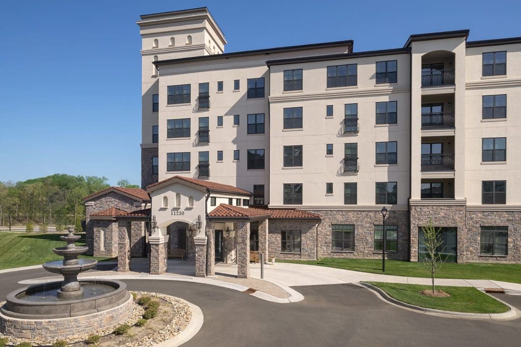 The Villas at Trevi Village in Charlotte, a Tuscan-style apartment building with a stone entrance and a fountain in the foreground.